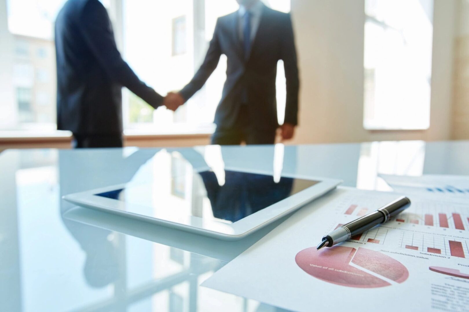 Two people shaking hands over a tablet